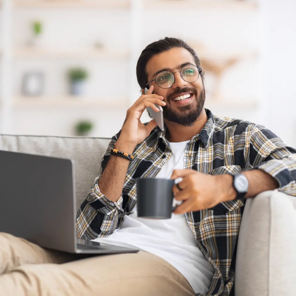 guy relaxing on the couch with coffee and laptop