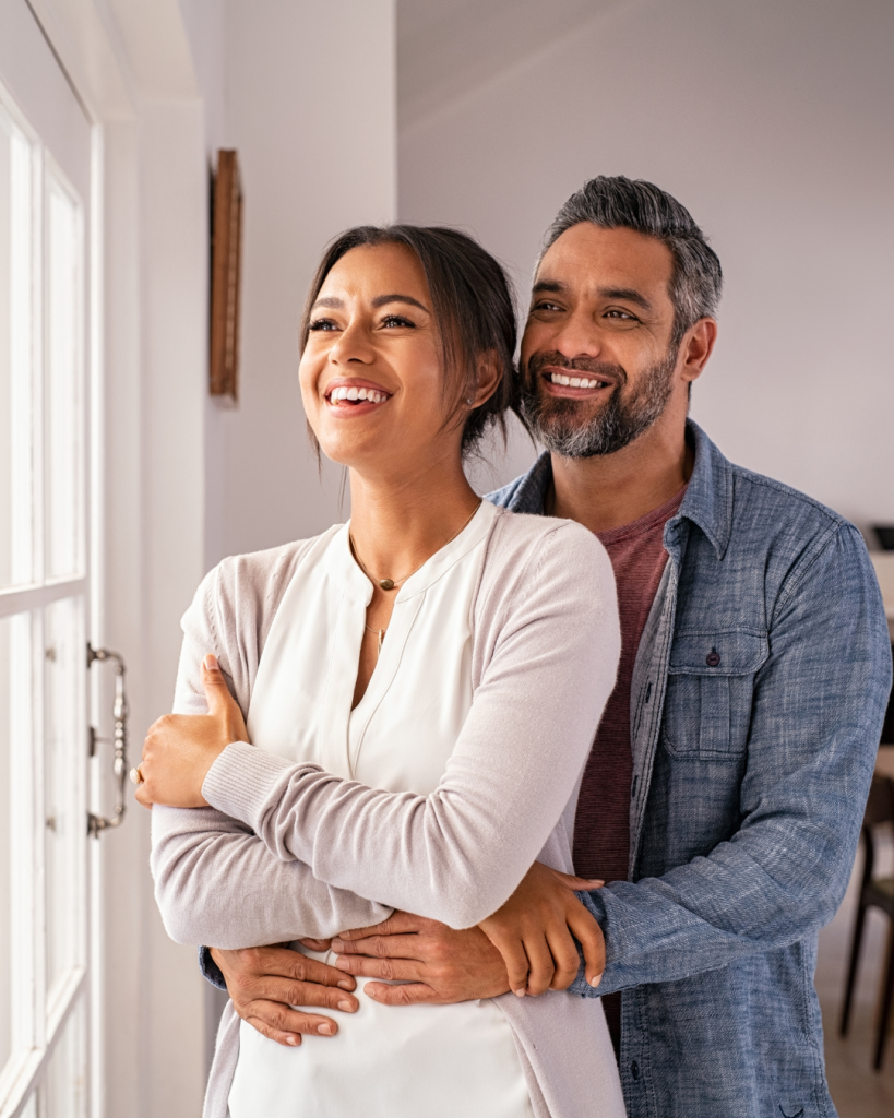 a mixed race couple looking out the window smiling